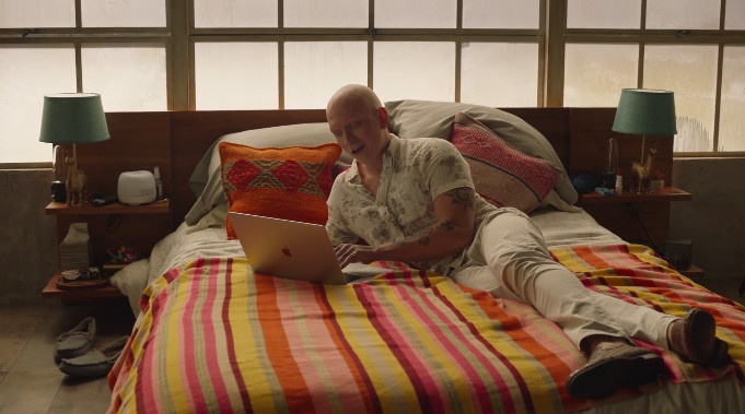 NoHo Hank lies on his bed on his laptop