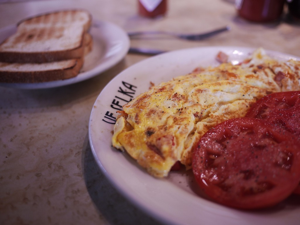 in the foreground, a plate of eggs and tomatoes at veselka in new york city; in the background, a plate of toast